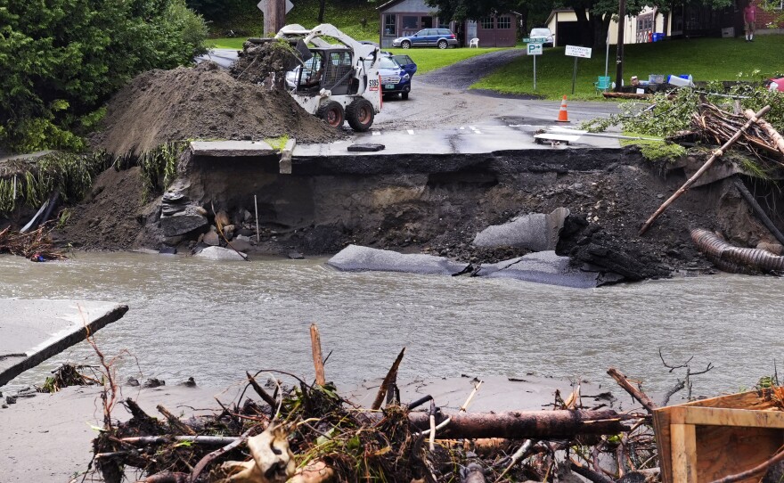 A loader dumps dirt along a washed out road