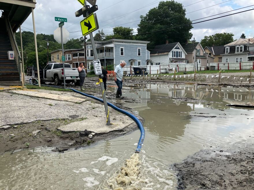 People walk through a street soaked with mud and water 