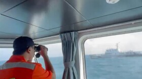 In this screen grab from video released by the Taiwan Coast Guard, a member of the Taiwan Coast Guard monitors a China Coast Guard boat as it passes near the coast of Matsu islands, Taiwan on Monday, Oct. 14, 2024.