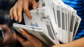 An election official organizes mail-in ballots to be sorted for the 2020 general election in West Chester, Pa.