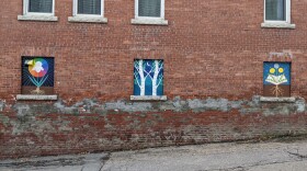 Three colorful murals depicting elements of nature sit on a brick wall off of Littleton's main street.