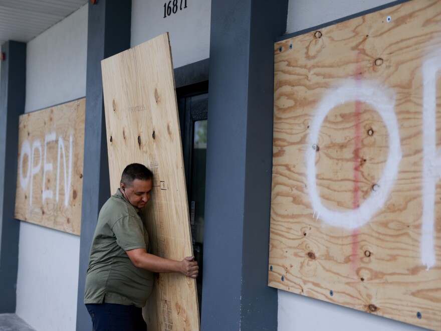 Salvador Gonzalez places plywood over the windows of a business before Hurricane Milton's arrival in Fort Myers, Florida.