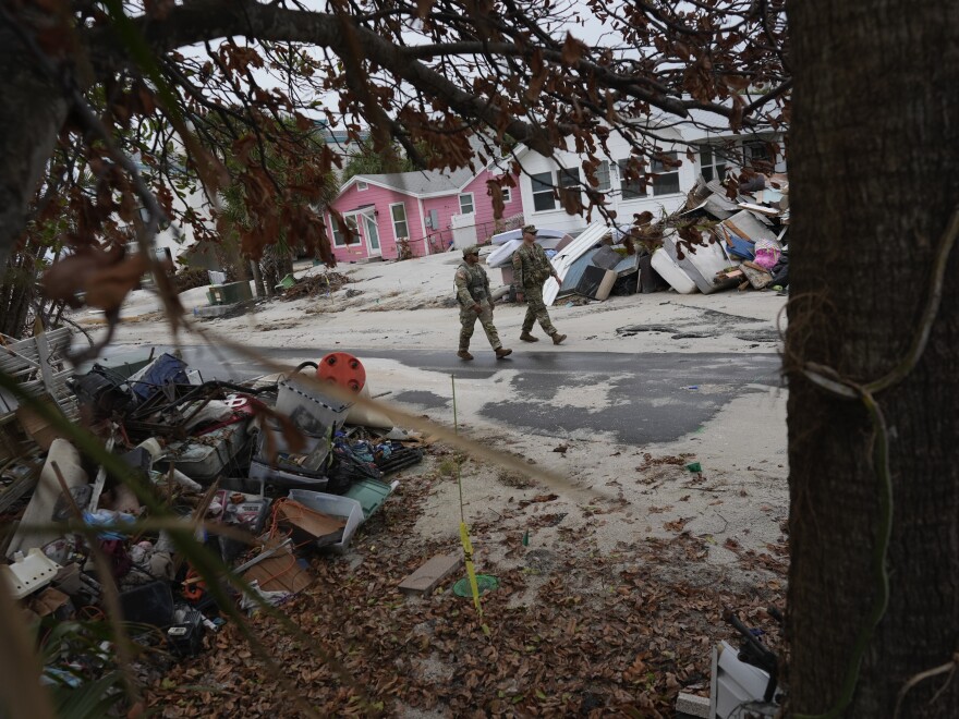 Members of the Florida Army National Guard check for any remaining residents in nearly-deserted Bradenton Beach, where piles of debris from Hurricane Helene still sit outside damaged homes, ahead of the arrival of Hurricane Milton, Tuesday, Oct. 8, 2024, on Anna Maria Island, Fla.