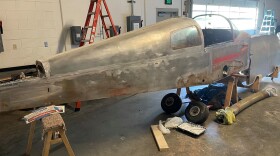 A small 1970's aircraft in a repair shop.