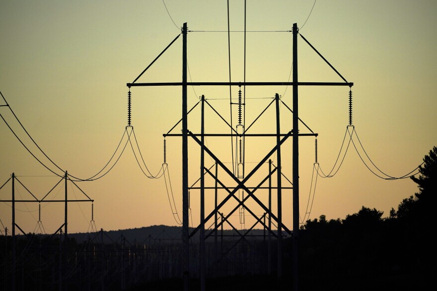 FILE - Power utility lines are seen, Wednesday, Oct. 6, 2021, in Pownal, Maine. A budget signed this week by Massachusetts Gov. Maura Healey clears the way for utilities to recover added costs caused by delays of a project to bring Canadian hydropower to the New England grid. The head of Central Maine Power’s corporate parent Avangrid previously said the cost of the $1 billion project grew to $1.5 billion because of delays and inflation during a prolonged court battle. (AP Photo/Robert F. Bukaty, File)