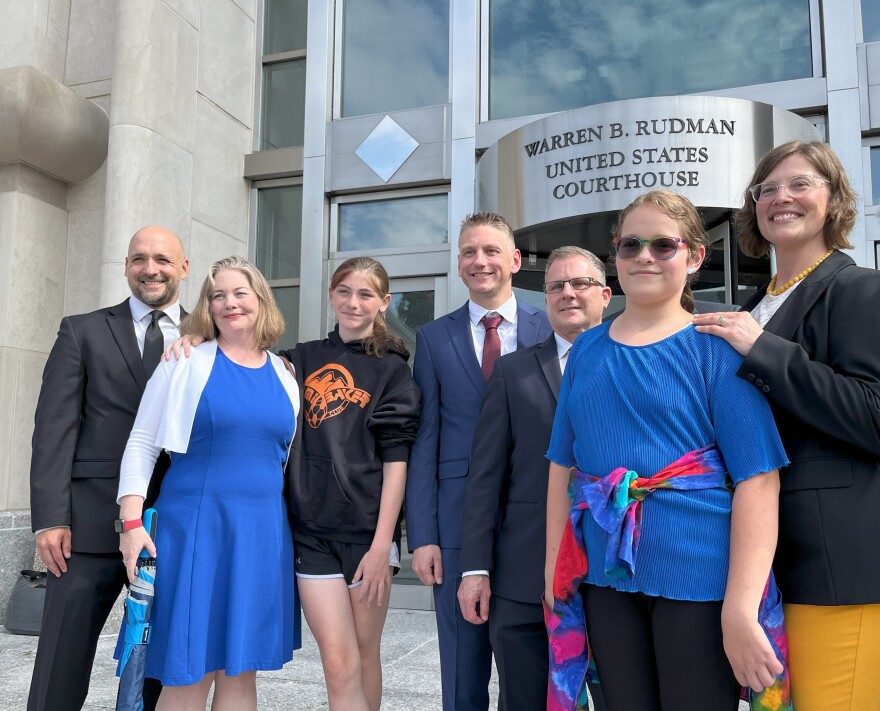 Parker Tirrell (third from left) and Iris Turmelle (second from right) gather outside the federal courthouse in Concord on Aug. 19, after a judge granted a temporary order allowing Tirrell to play for her school's soccer team. Tirrell and Turmelle are plaintiffs in a lawsuit challenging a new law that bans transgender girls from playing on girls' sports teams. They're joined here by their mothers and members of their legal team.