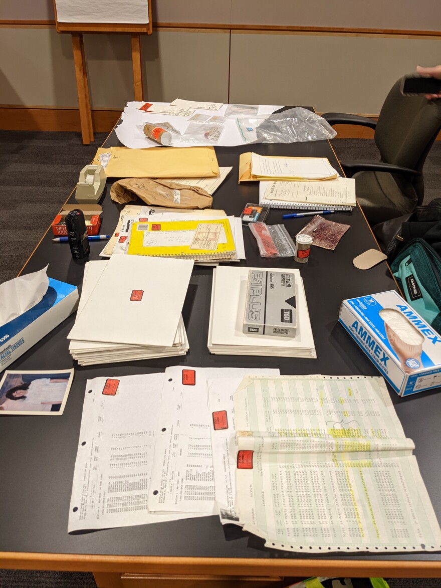 The contents of a box of newly rediscovered evidence in the Jason Carroll case are laid out on a table in a New Hampshire courtroom in October 2022. The contents include documents, a photo of Sharon Johnson, and a videotape of the crime scene where her body was discovered.