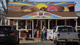 A customer holds the door for a family arriving at Leavitt's Country Bakery, Thursday, April 13, 2023, in Conway, N.H. The large painting of pastries created by students and displayed over the bakery is at the center of a legal battle pitting a zoning ordinance against freedom-of-speech rights. (AP Photo/Robert F. Bukaty)