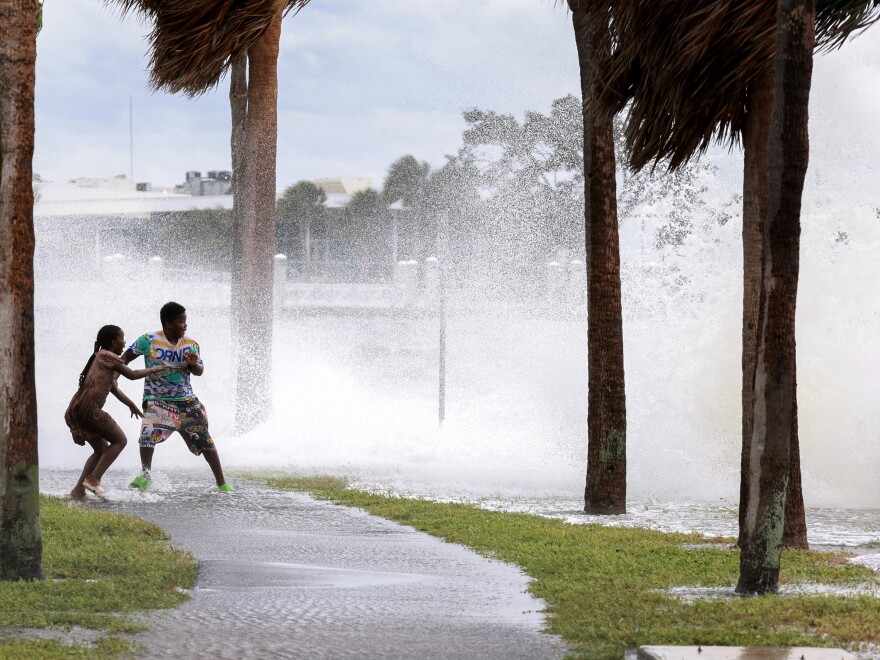 People are splashed by churning surf from Tampa Bay as Hurricane Helene passes offshore on Sept. 26, 2024, in St. Petersburg, Fla. 