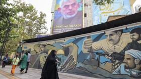 People walk past a billboard showing a portrait of Hamas leader Yahya Sinwar (top) next to Palestine Square in the Tehran on Aug. 12, 2024.