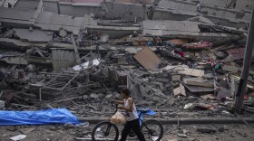 FILE - A Palestinian child walks with a bicycle by the rubble of a building after it was hit by an Israeli airstrike, in Gaza City, Sunday, Oct. 8, 2023. A new U.N. report paints a stark picture of the devastating collapsing Palestinian economy after a month of war and Israel’s near total siege of Gaza. (AP Photo/Fatima Shbair, File)