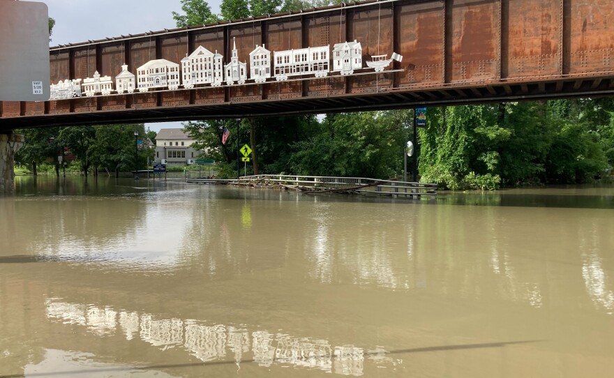 Brown water covers a road underneath and red bridge.