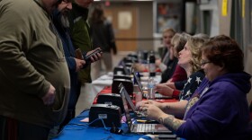 MJ McCobb, 43, second from right, helps already-registered voters get checked into vote at Milford High School on Tuesday, Jan. 23, 2023, in Milford, N.H. (Raquel C. Zaldívar/New England News Collaborative)