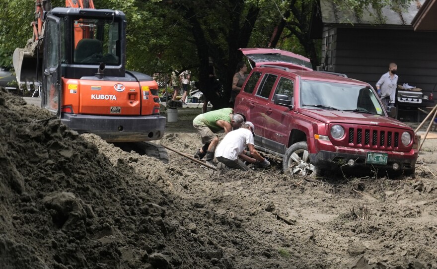 Two men dig out an SUV stuck in the mud 