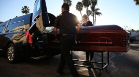 Embalmer and funeral director Kristy Oliver (R) and funeral attendant Sam Deras load the casket of a person who died after contracting COVID-19 into a hearse at East County Mortuary in El Cajon, California.