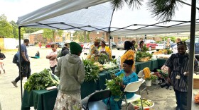 People sit at tables piled high with produce