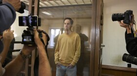 <em>Wall Street Journal</em> reporter Evan Gershkovich stands in the glass defendant's booth at the Moscow City Court, in Moscow on Sept. 19, 2023. 