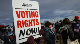 A person holds a sign that says "VOTING RIGHTS NOW" during a peace walk in Washington, D.C., on Martin Luther King Jr. Day in 2022.