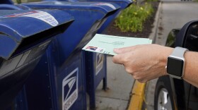 A person drops applications for mail-in-ballots into a mailbox in 2020 in Omaha, Neb.