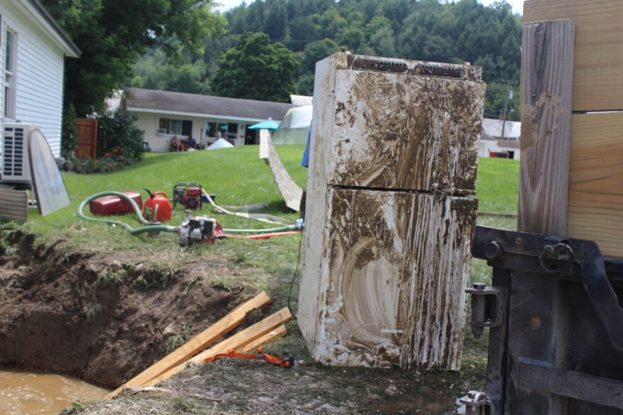 A muddy fridge sits outside of a building