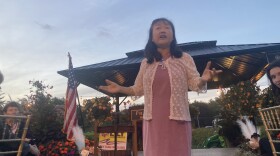 Lily Tang Williams stands on a stage and speaks to supporters.