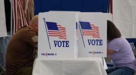 Two people sit at a table to fill out election day ballots.