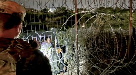 New Hampshire National Guard Sgt. Timothy King keeps watch on four people at the border in Eagle Pass, Texas. Hours later, they cut the fence upriver, climbed through, and asked to be turned over to the authorities.