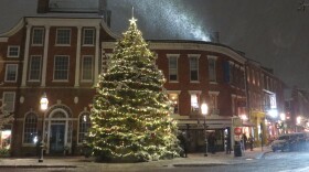 A lit Christmas tree in Portsmouth's Market Square on a snowy night.