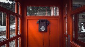 A rotary phone in a mysterious red booth.