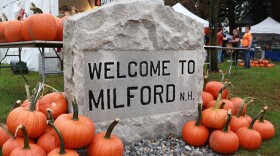 A stone sign that reads "Welcome to Milford, N.H." surrounded by pumpkins at the 2023 Milford Pumpkin Festival