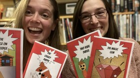 Brittany McGuire and Jackie Benson holding examples of their comic books, including "The Crazy Puppy" and "Two Rude Dudes. 