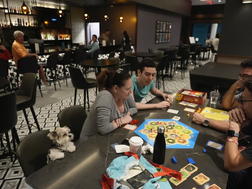 The Segundo family, who evacuated from nearby Davis Island, plays a board game with their dog Cassie looking on, as Hurricane Milton makes landfall on Florida's Gulf Coast, at Hyatt Place Tampa Downtown hotel in Tampa, Fla.,