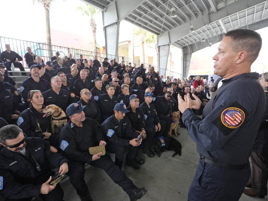 Miami-Dade Fire Rescue's Urban Search and Rescue Florida Task Force One leader Brandon Webb, right, addresses members of the task force before they deploy ahead of Hurricane Milton in Doral, Fla.