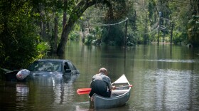 After speaking with members of Hillsborough County Fire Rescue, a man paddles back into a flooded neighborhood in Valrico, Fla. Flooding from a nearby waterway turned some neighborhoods into rivers, forcing dozens to evacuate their homes.