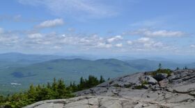 A photo of Mt. Kearsarge's rocky summit, with views of more summits in the distance. 