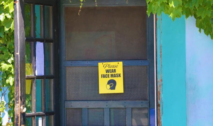 A sign on the door of Ceres Bakery in Portsmouth reads "Please wear face mask"