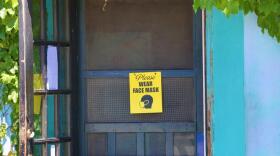 A sign on the door of Ceres Bakery in Portsmouth reads "Please wear face mask"