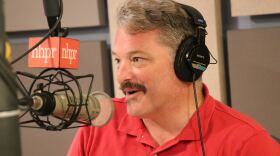 A man in a red shirt talks in front of a mic