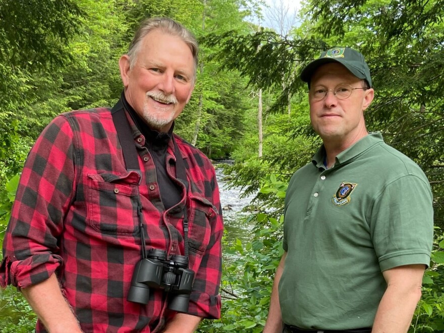 Two men stand by a river.