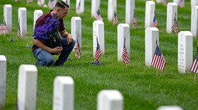 A man places flowers in front of headstones in Section 60, which mark the final resting place of service men and women at Arlington National Cemetery on May 27 in Arlington, Va.